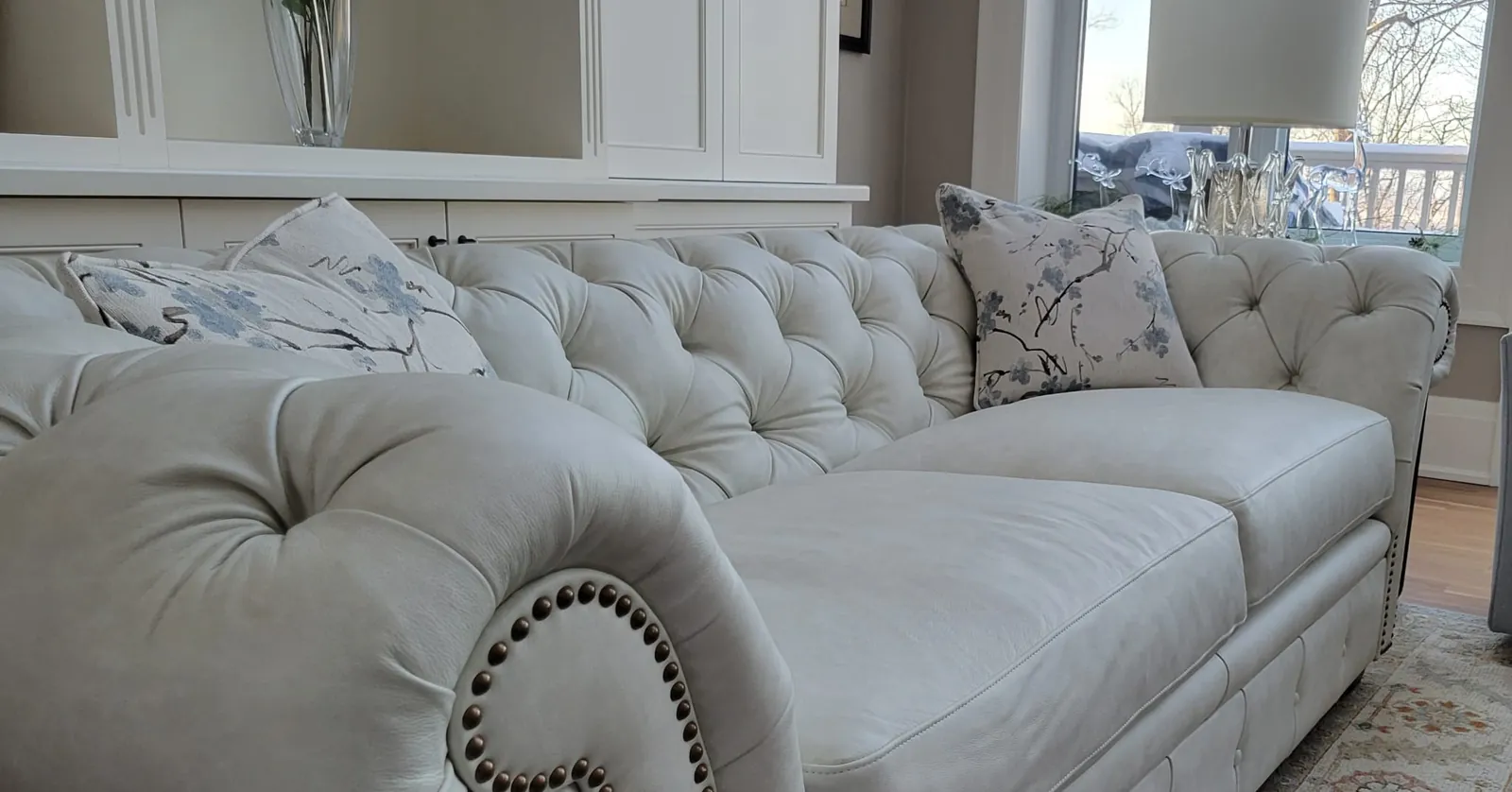 A white tufted leather sofa with nailhead trim in a Huntsville living room furnished by Uptown Living