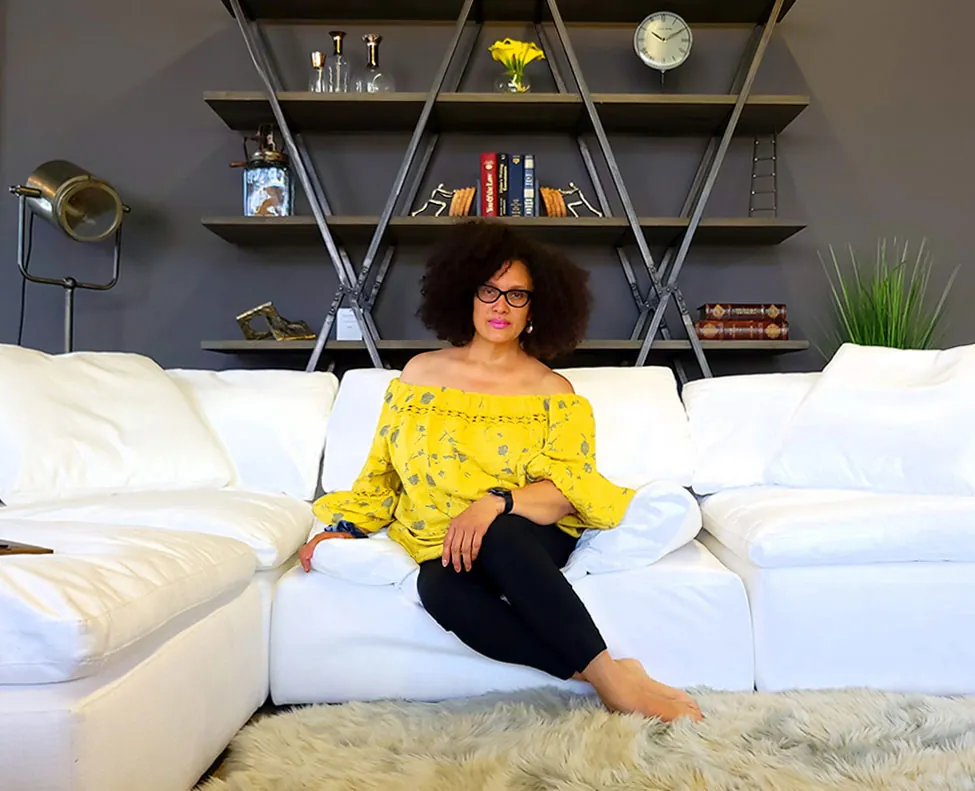 Elena Villalba, owner and designer of Uptown Living, seated on a white sectional in the showroom